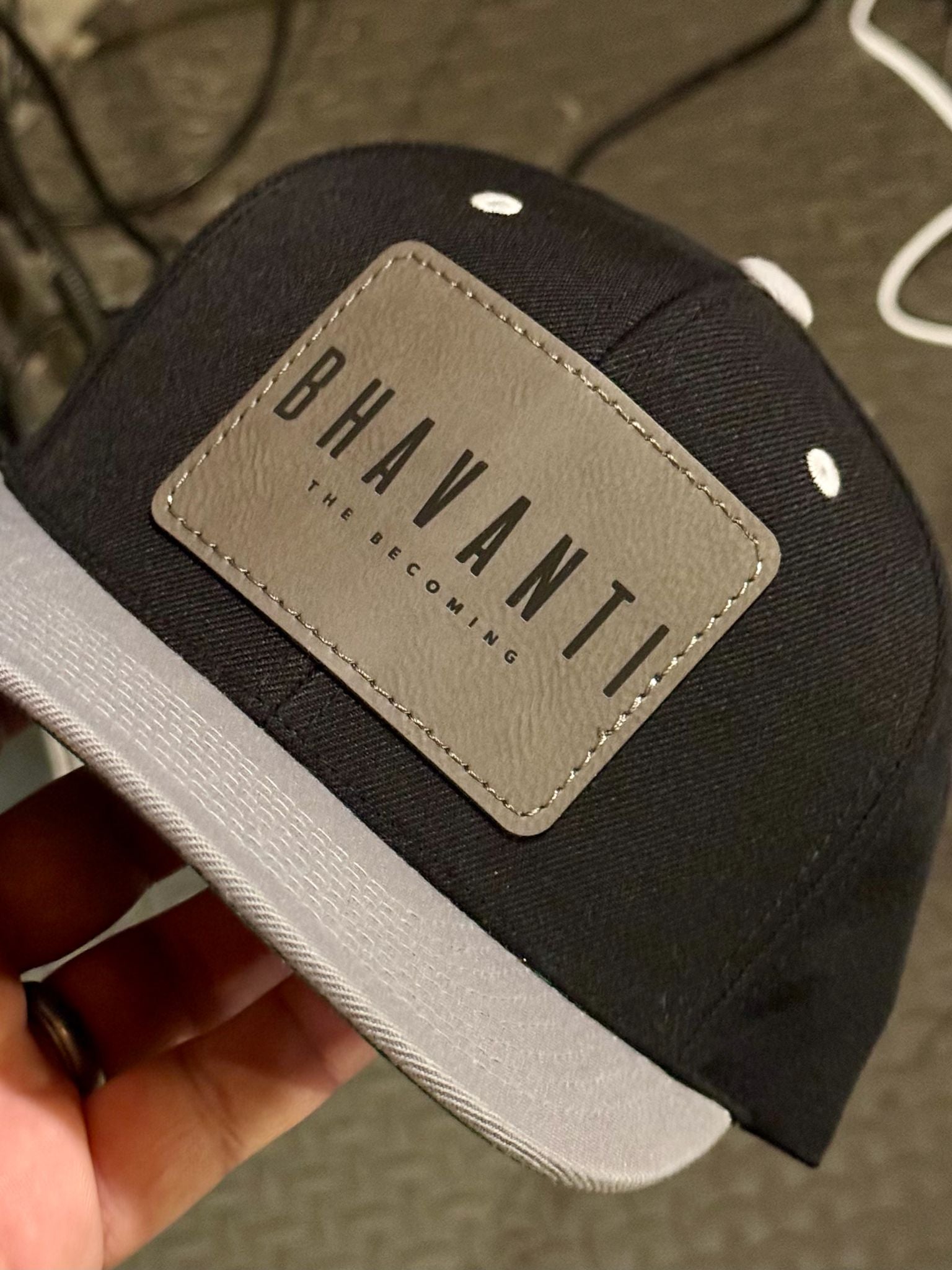 Black Bhavanti cap with premium brown label detail on patterned background